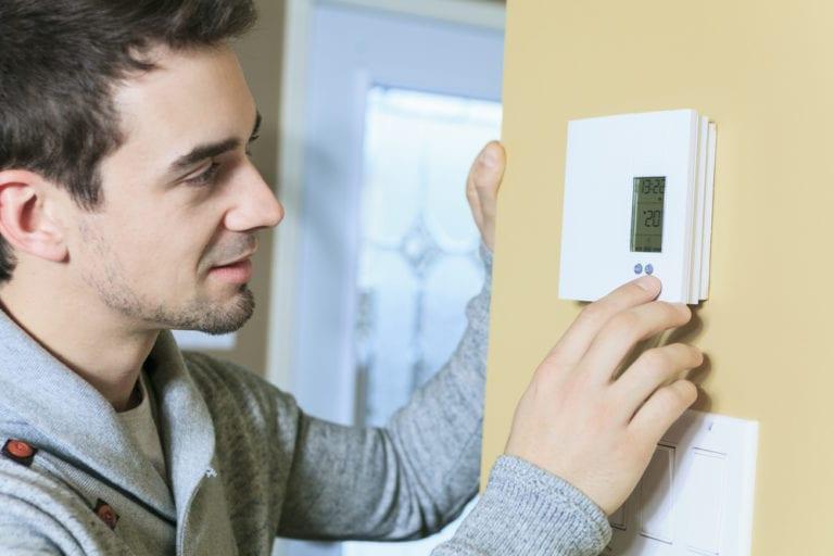 Man touching his thermostat